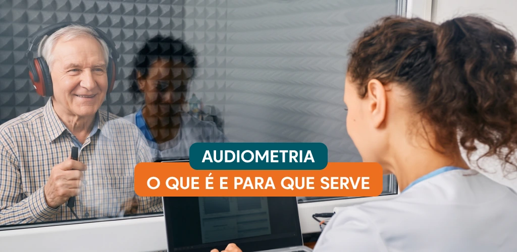 Idoso dentro de cabine acústica com fones de ouvido sinalizando percepção de som durante exame de audiometria realizado por fonoaudióloga.